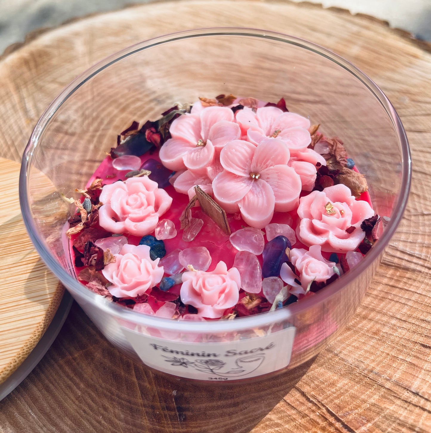 Bougie féminin sacré de Onéotéa, ornée de fleurs roses et de pierres naturelles, inspirée par l'énergie féminine divine. Un hommage au Féminin sacré, cette bougie incarne l'harmonie entre femme et nature, renforçant la connexion spirituelle et l'amour de soi.