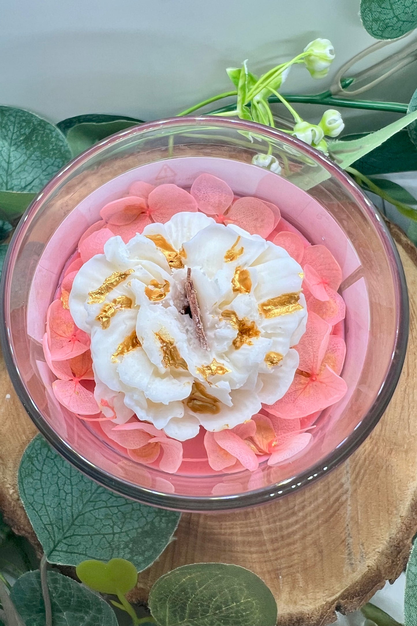 Bougie parfumée Ambre Patchouli & Rose éternelle by Onéotéa - Éveil des Sens, avec une décoration florale délicate et un soupçon d'or, entourée de pétales roses.