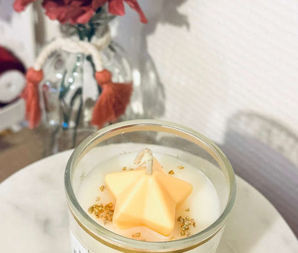 Bougie parfumée Éclat Lunaire avec notes fruitées, florales, ambrées et vanillées dans un contenant en verre avec paillettes d'or
