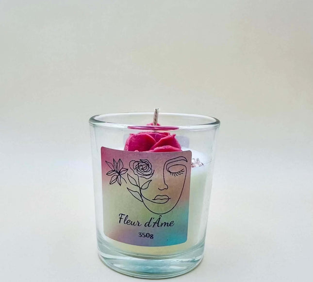 Bougie Fleur de l'Âme en cire blanche dans un verre transparent, avec une rose rose et une étiquette illustrée irisée
