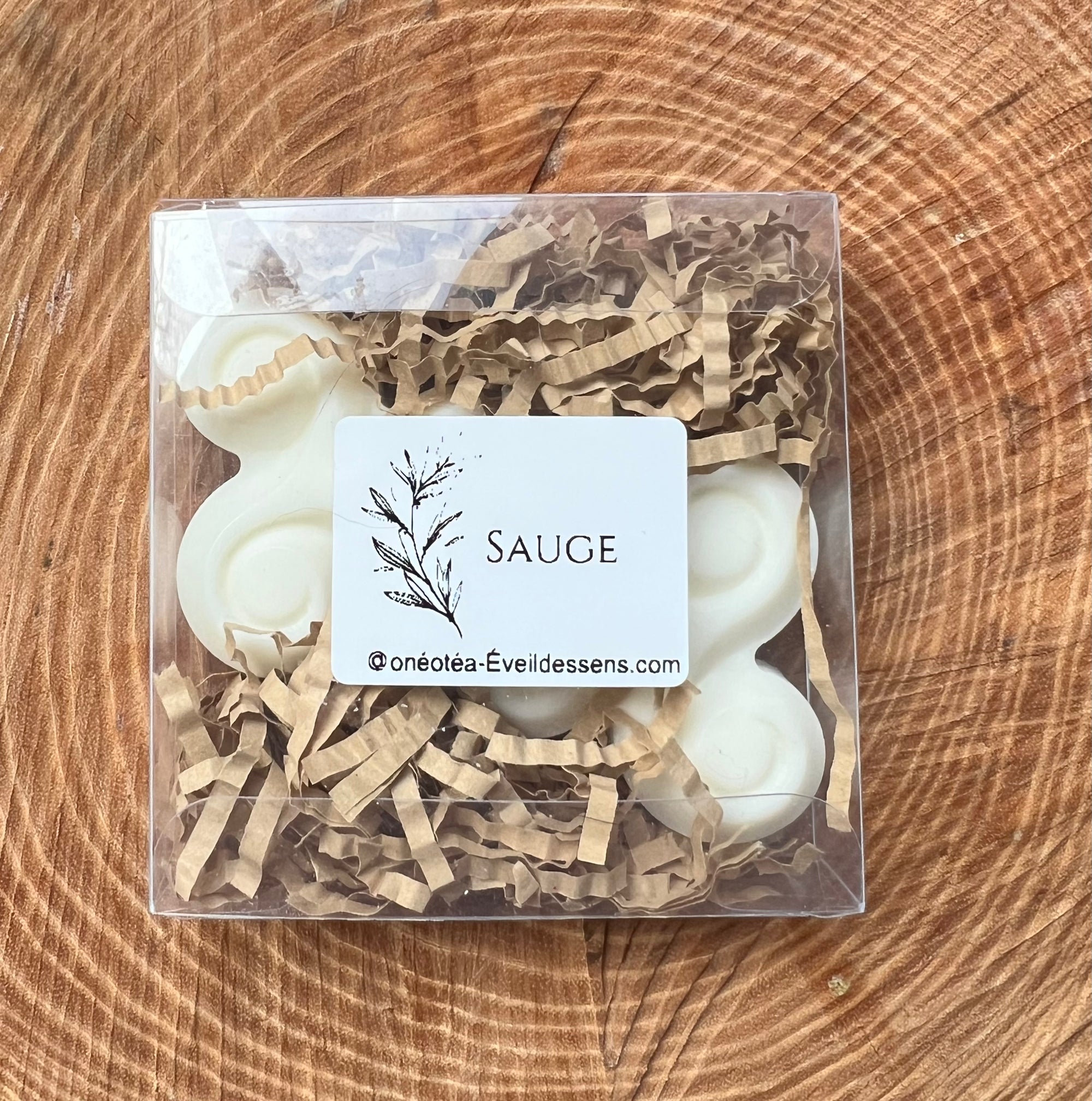 Vue rapprochée d'une boîte de fondants parfumés à la sauge, avec du papier de remplissage en kraft et une étiquette décrivant le produit.