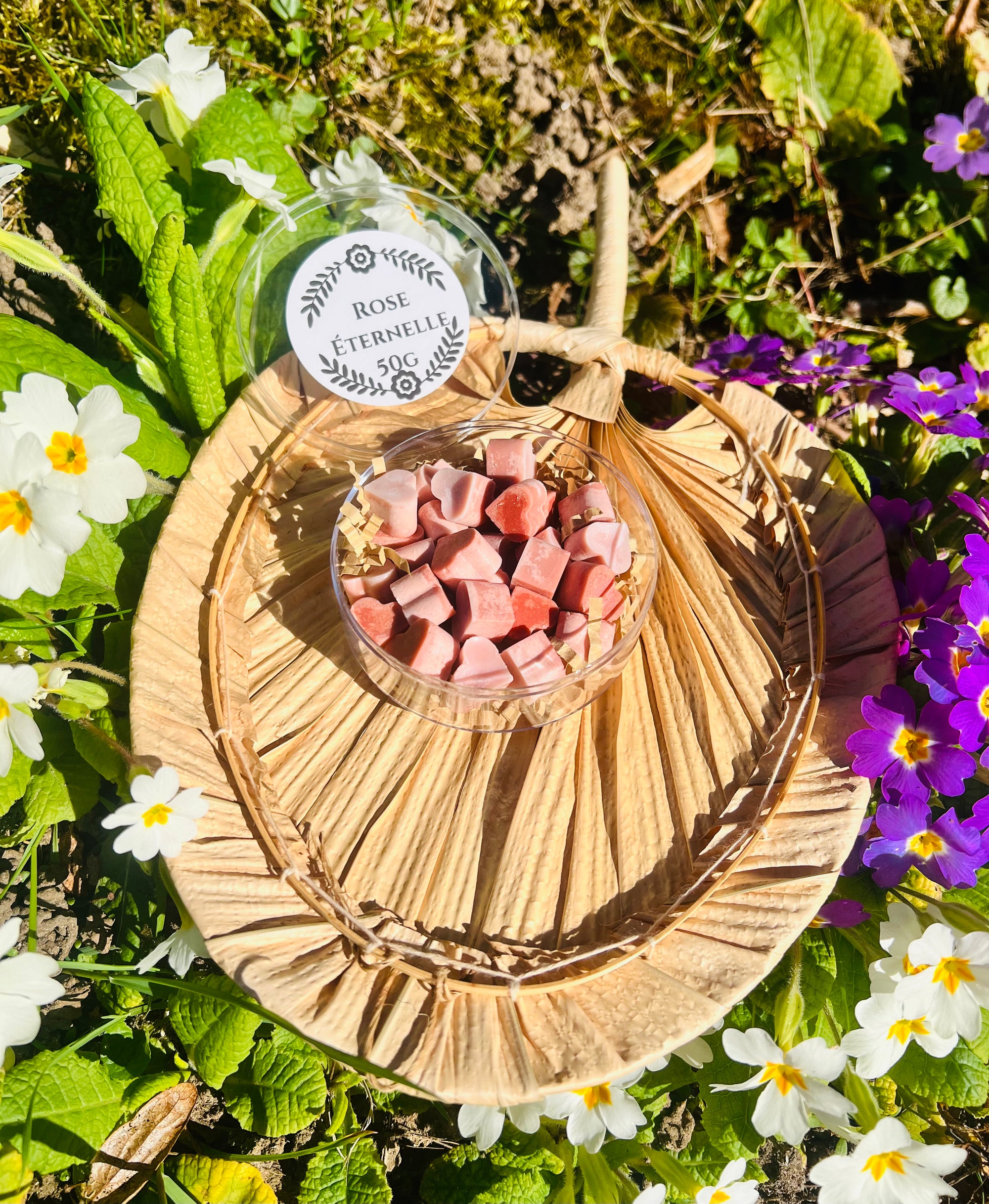 Vue rapprochée des fondants parfumés 'Rose éternelle' de Onéotéa - Éveil des Sens, disposés dans une boîte, sur un plateau en osier, embelli par des fleurs sauvages. Ces petits coeurs parfumés offrent une expérience olfactive florale, ajoutant une atmosphère chaleureuse à tout espace.